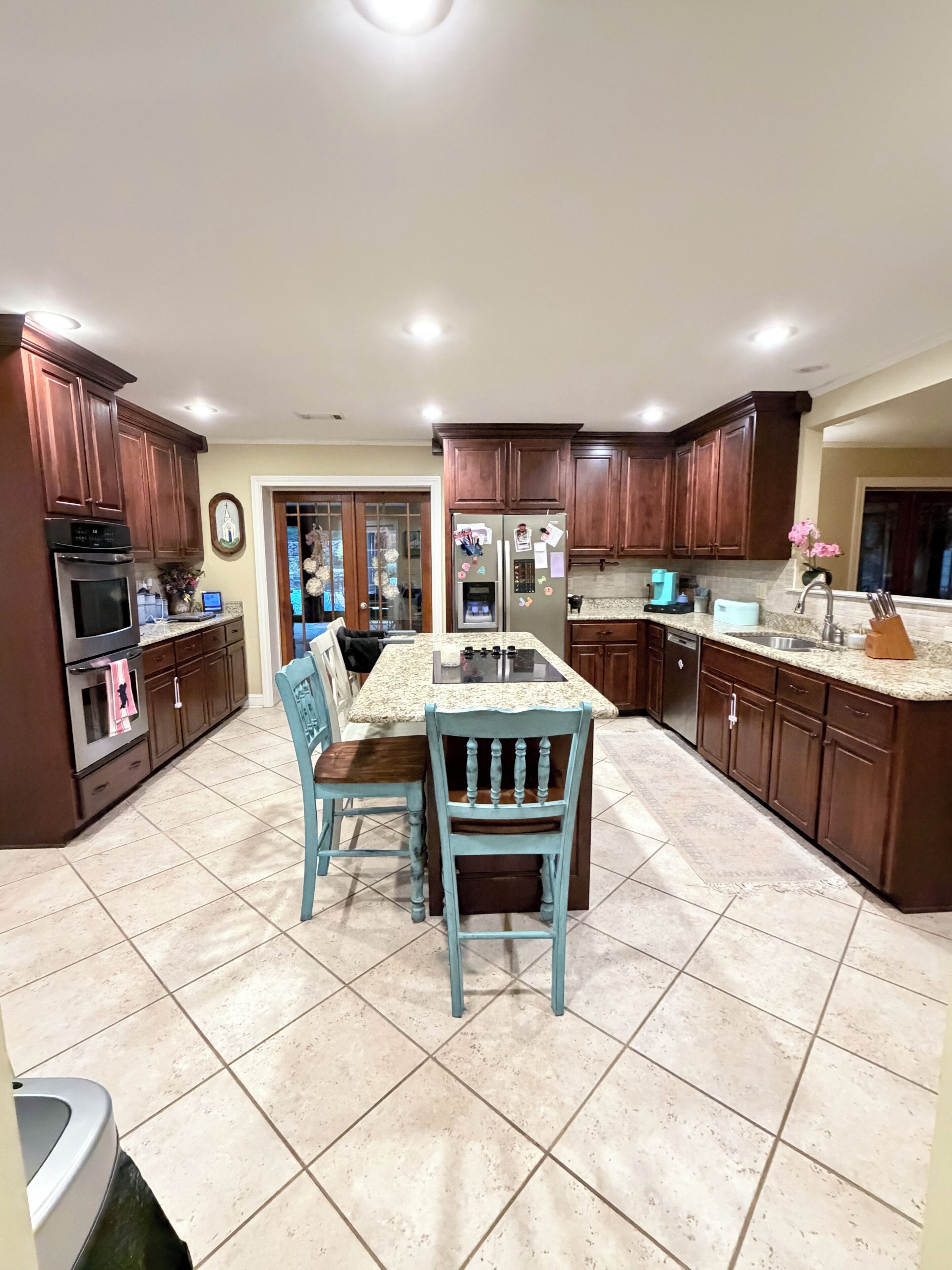 A kitchen with wooden cabinets, a central island, and a dining table with chairs.