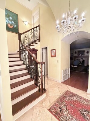 A grand staircase with ornate railings, a chandelier, and a patterned rug. - Less than 1 Mile From the Square and Campus- Huge Sunroom- Sleeps 9 (Oxford)