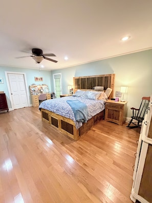 Un dormitorio con una cama de madera, un ventilador de techo y una mesita de noche con una lámpara.