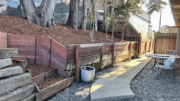 Un espace jardin agrémenté d’un banc en bois, d’un chemin en béton et d’une clôture en bois.