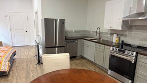 Una cucina moderna con elettrodomestici in acciaio inossidabile, un tavolo da pranzo in legno e mobili chiari.