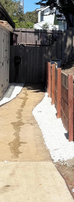 A concrete pathway leading to a wooden fence with a white border.
