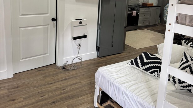 Una camera da letto moderna con un letto, una TV a parete e un angolo cottura sullo sfondo.