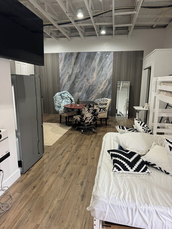 Un dormitorio con cama, escritorio, silla, armario y espejo.