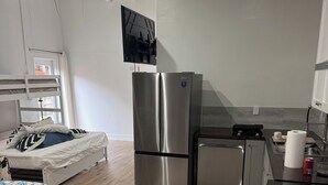 Una cucina moderna con elettrodomestici in acciaio inossidabile, un letto con biancheria a motivi e vista sull'esterno.