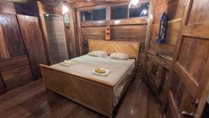 A wooden room with a bed, a window, and a wooden wardrobe.