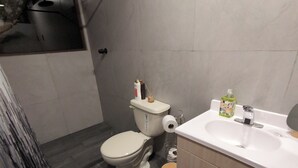 A modern bathroom with a toilet, sink, and shower.