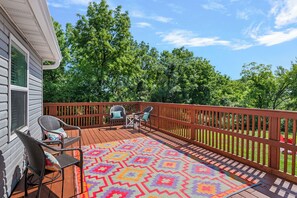 A wooden deck with outdoor furniture and a colorful rug.