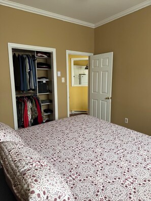 A bedroom with a bed, a closet, and a door leading to a bathroom. - A Cozy Stay on Coronation Street (St. John's)