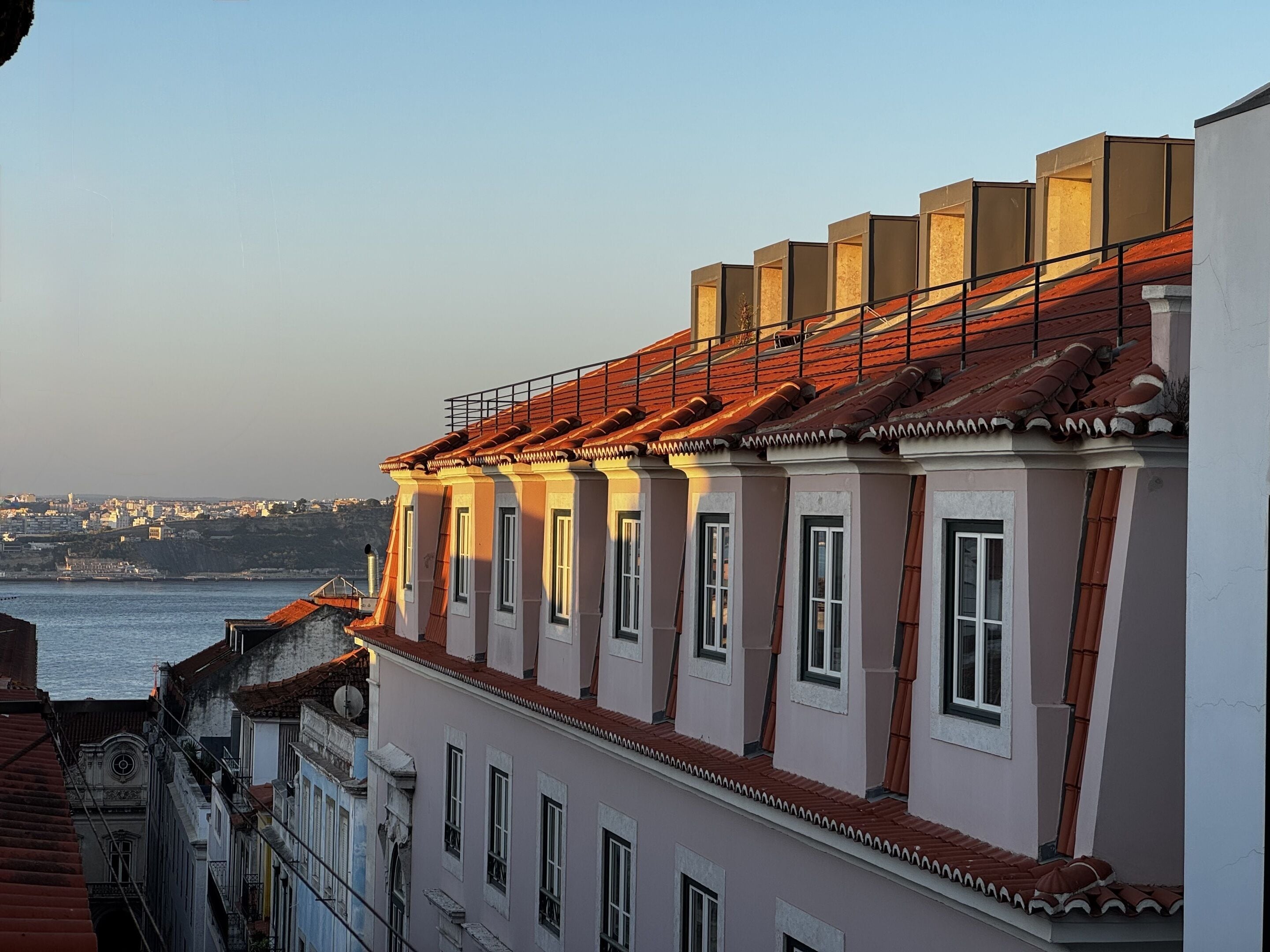 Una hilera de edificios con techo de tejas rojas, paredes blancas y numerosas ventanas.