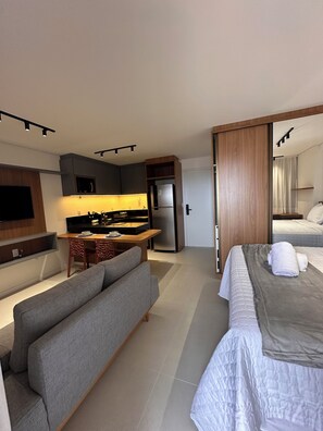 A modern hotel room with a sofa, a bed, a kitchenette, and a large mirror. - Cozy 1-bedroom apartment in marvelous Fortaleza with AC and gym (Fortaleza)