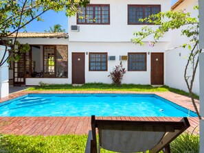 Un bâtiment à deux étages doté d’une piscine, d’un patio couvert et d’un petit jardin.