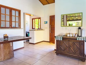 Uma cozinha com mesa de madeira, um armário com espelho e uma porta que dá para outro cômodo.
