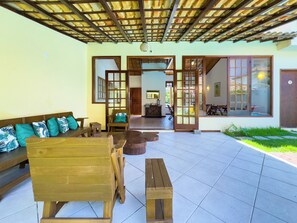Un patio amplio con un banco de madera, una mesita pequeña y un sofá con cojines estampados.