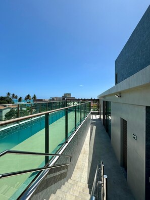 Ein Poolbereich mit klarem, blauem Wasser, einer Glasbrüstung und einer Treppe, die hinunterführt.