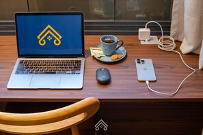 A laptop, smartphone, mouse, and a cup of tea on a wooden desk. - 200m from Paulista Avenue, studio in Jardins | LYVVO (São Paulo)