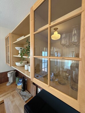A kitchen with wooden cabinets, a coffee maker, and a black countertop. - Charming Furnished Casita with Private Yard in South Park/Golden Hill (San Diego)