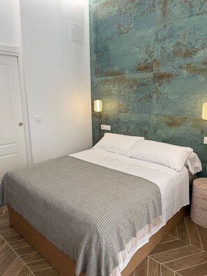 Ein Schlafzimmer mit einem Bett, einer Wandleuchte und einer Tür.