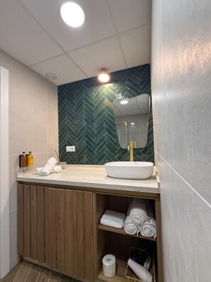 Ein modernes Badezimmer mit einer Wand im Fischschuppenmuster, einem weißen Waschbecken und einer Holzkommode.