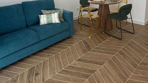 A modern living room with a blue sofa, a dining table with chairs, and a herringbone-patterned wooden floor. - La Casona de les Arts 1 - Oceanográfic (València)