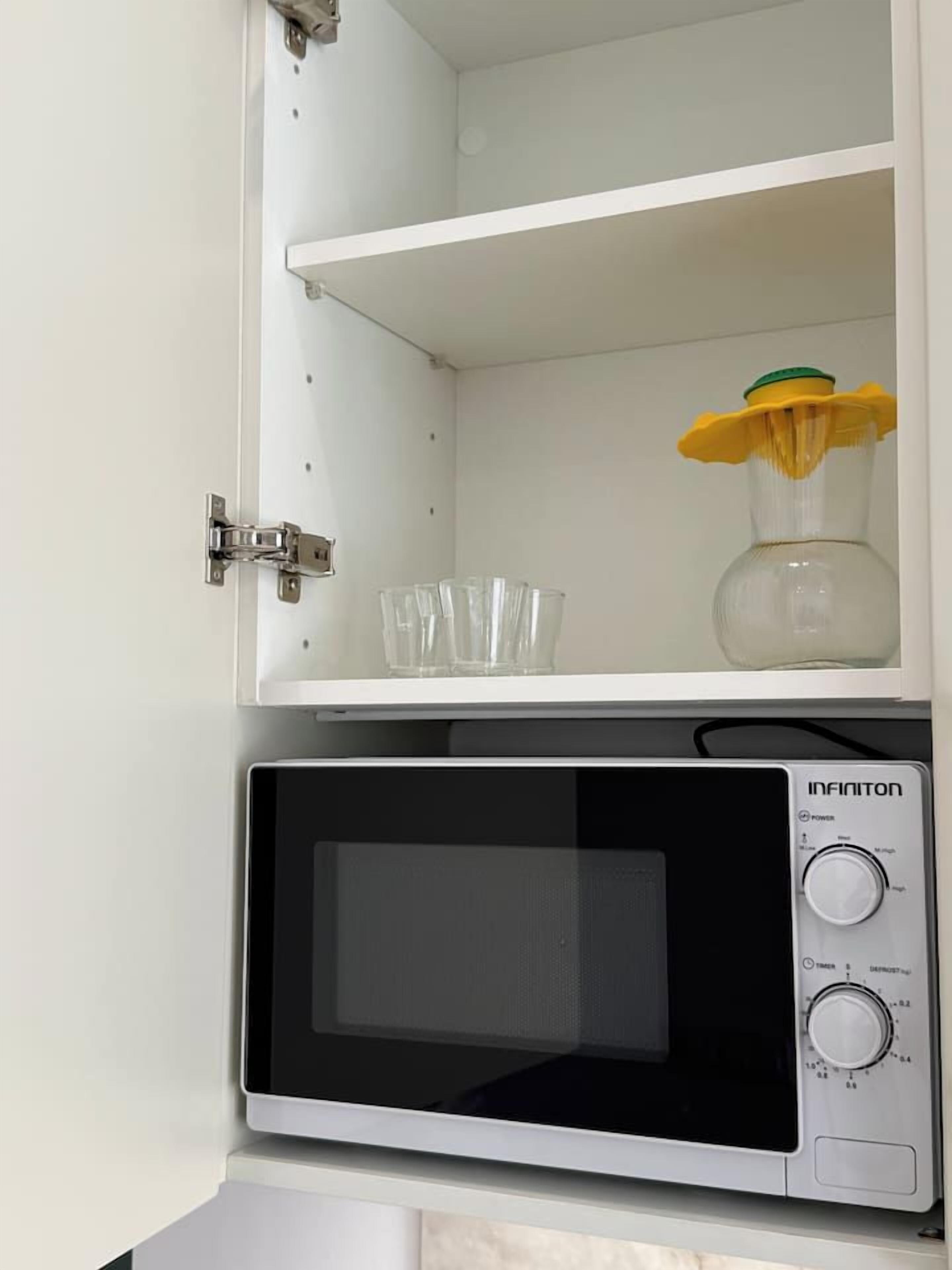 Eine Mikrowelle mit digitaler Anzeige und Bedienfeld, auf einer weißen Arbeitsplatte platziert.