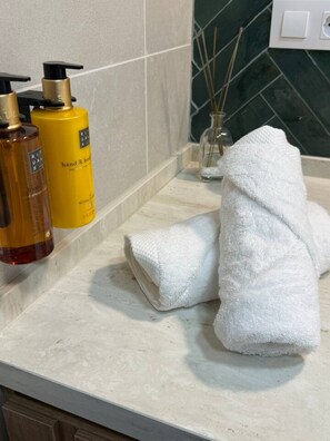 A bathroom counter with toiletries, a glass vase with reeds, and a white towel. - La Casona de les Arts 1 - Oceanográfic (València)