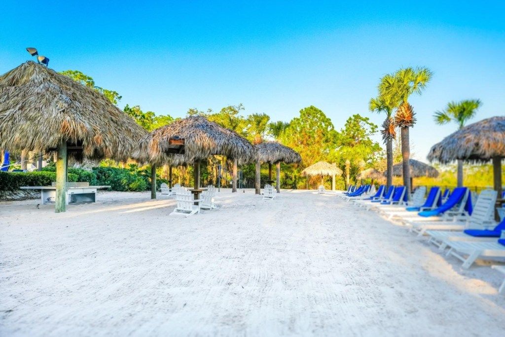 A beach with thatched umbrellas and sun loungers.