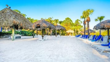A beach with thatched umbrellas and sun loungers.