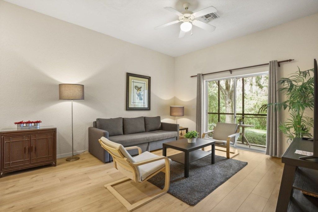 A living room with a sofa, armchair, coffee table, and a ceiling fan.