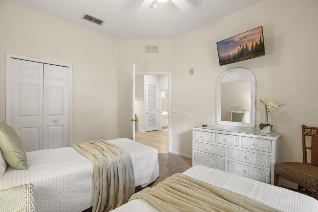 A bedroom with two beds, a dresser, a mirror, and a painting on the wall.
