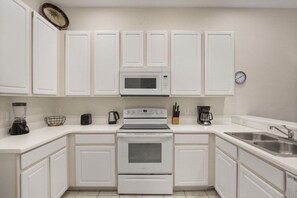 A kitchen with white cabinets, a microwave, an oven, a coffee maker, and a sink. - Great Amenities 3 BD/ 2 BA/ Bahama Bay - 605 NP (Davenport)