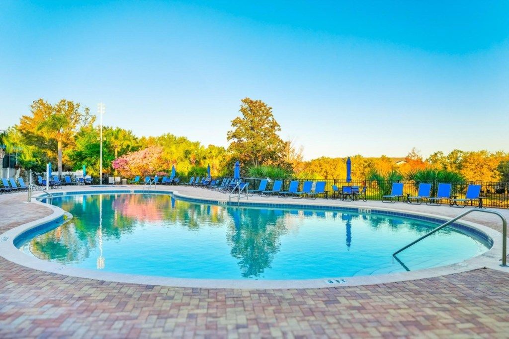 A swimming pool with lounge chairs and a brick patio.