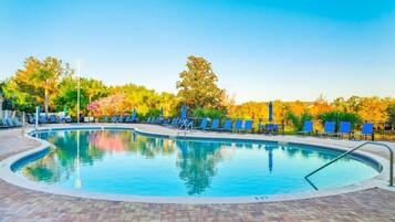 A swimming pool with lounge chairs and a brick patio.