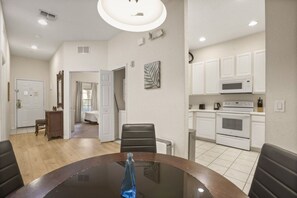 A modern kitchen with white cabinets, a microwave, and an oven. There is a dining area with a glass table and chairs. - Great Amenities 3 BD/ 2 BA/ Bahama Bay - 605 NP (Davenport)