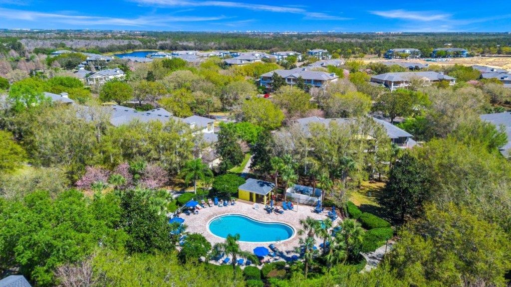 A residential area with a swimming pool surrounded by lounge chairs and a small building, likely a clubhouse or pool house.