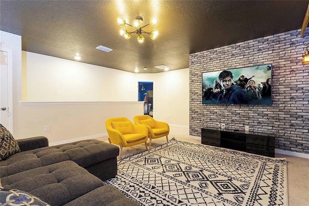 Ein Wohnzimmer mit Kamin, Fernseher an einer Ziegelwand und einem gemusterten Teppich.