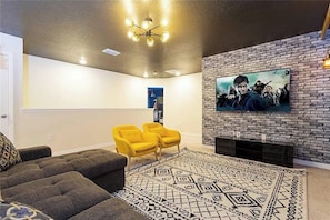 Una sala de estar con chimenea, un televisor montado en una pared de ladrillo y una alfombra estampada.