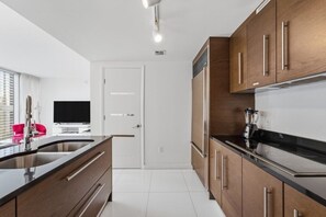 Eine moderne Küche mit Holzausstattung, Edelstahlgeräten und einer schwarzen Arbeitsplatte.