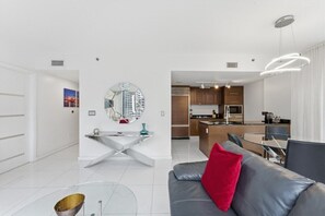 A modern living room with a grey sofa, a red pillow, and a glass coffee table. - 2 BD/ 2 BA/ Iconbrickell (3104 BA) (Miami)