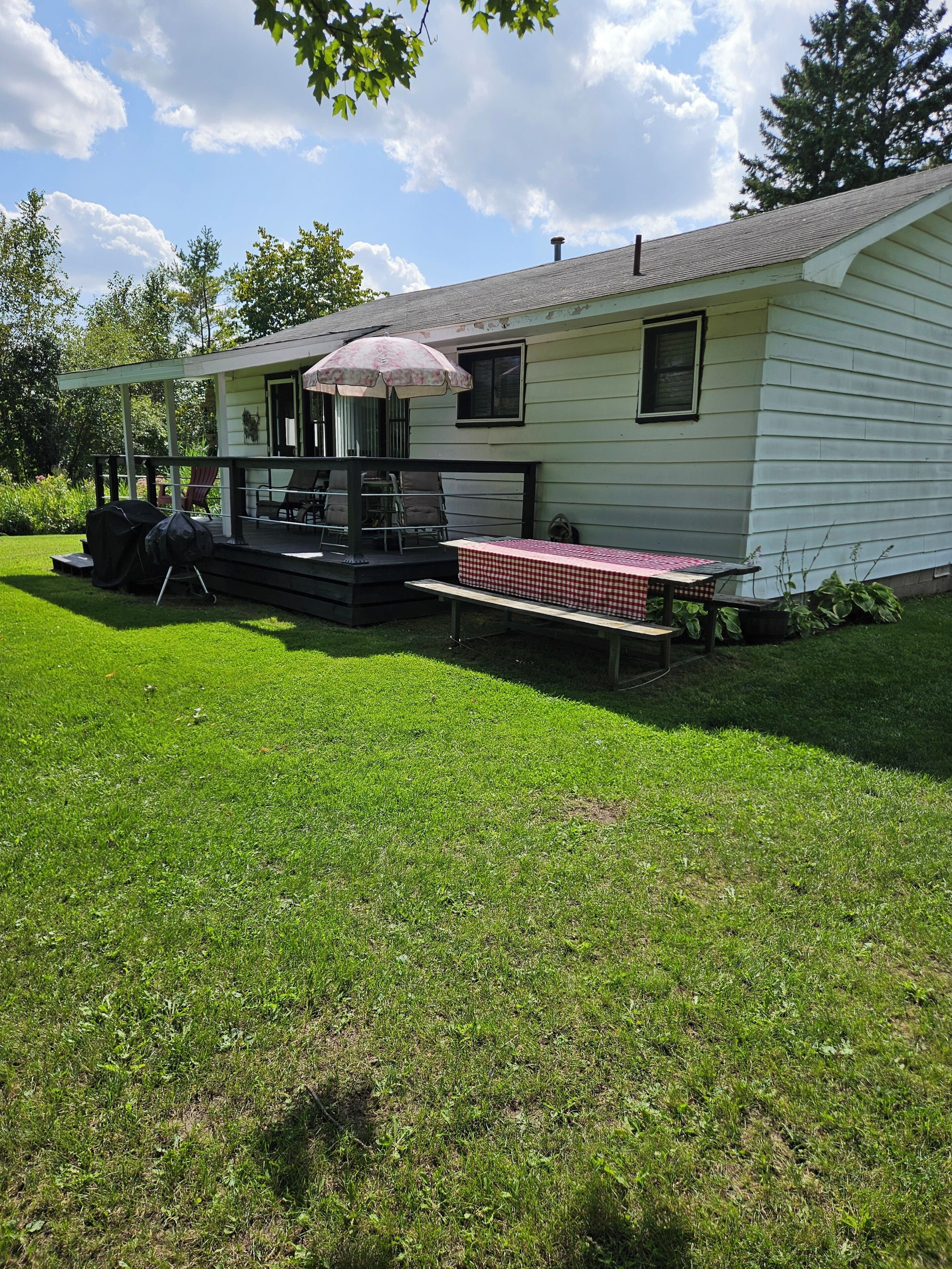 A house with a covered porch, a grill, and a picnic table.