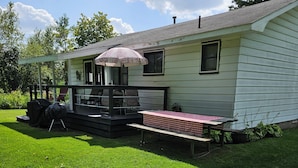 Une maison avec un porche abrité, un barbecue et une table de pique-nique.