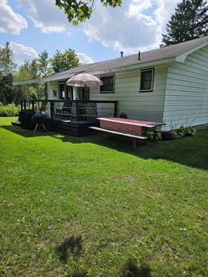 A house with a covered porch, a grill, and a picnic table.