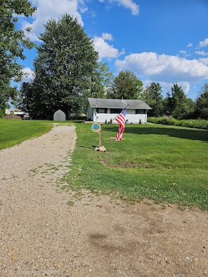 A gravel path leading to a white building with a flagpole and American flag.