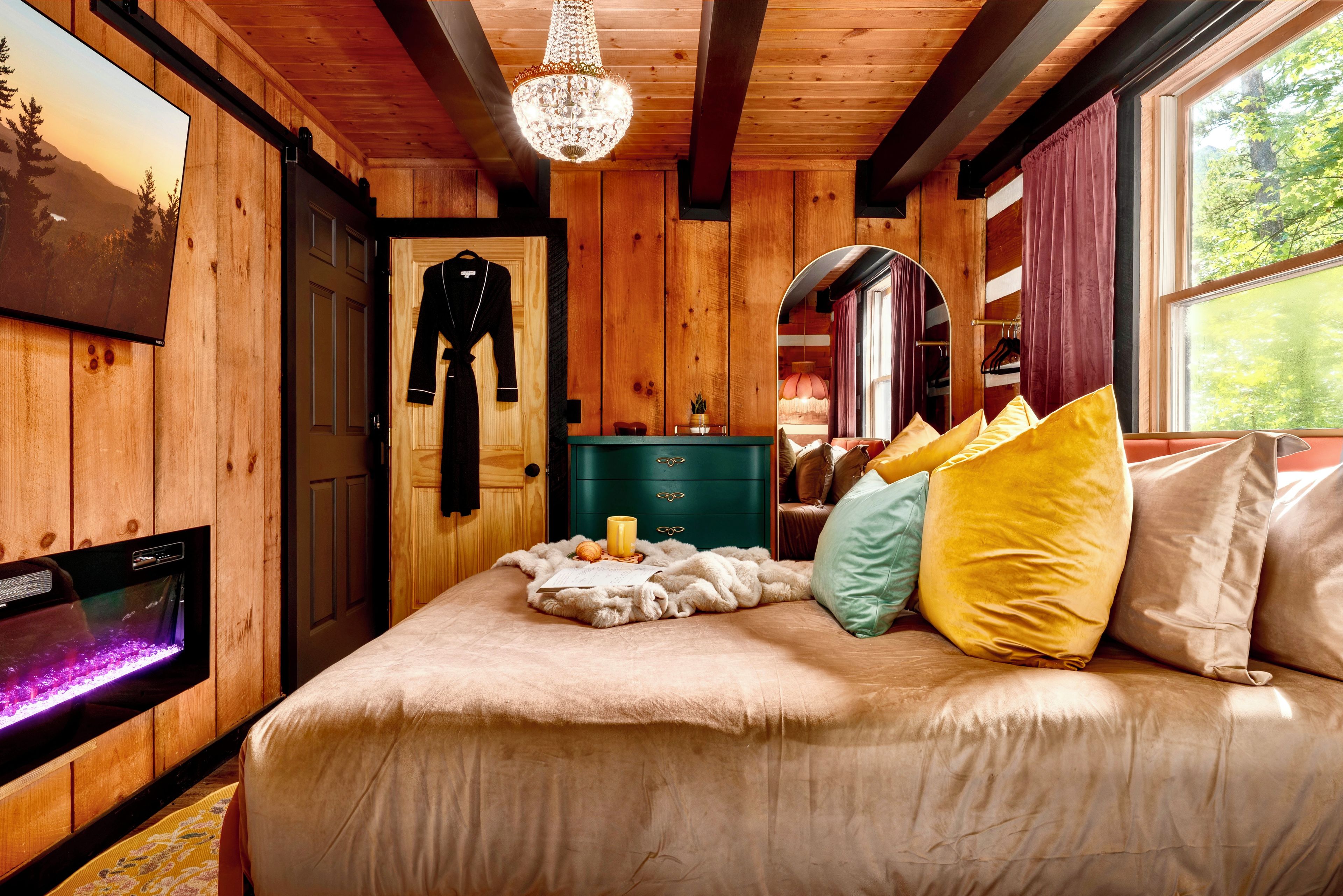 A wooden room with a bed, a television, and a chandelier.