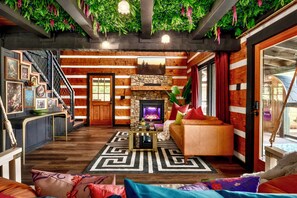 A cozy living room with a fireplace, wooden walls, and a staircase. - ★PrivateCouplesSpa★MtnView★SAUNA★OutdoorTub★FirePit★ (Sevierville)