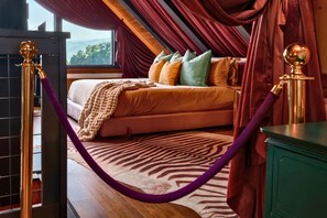 Quarto com cama, travesseiros, tapete com padrão de zebra e vista para o exterior.