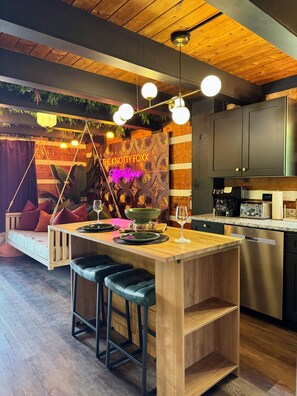 A modern kitchen with a wooden island, bar stools, a neon sign, and a hanging light fixture. - ★PrivateCouplesSpa★MtnView★SAUNA★OutdoorTub★FirePit★ (Sevierville)