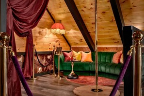 A cozy room with a green sofa, a red lamp, and a wooden ceiling. - ★PrivateCouplesSpa★MtnView★SAUNA★OutdoorTub★FirePit★ (Sevierville)