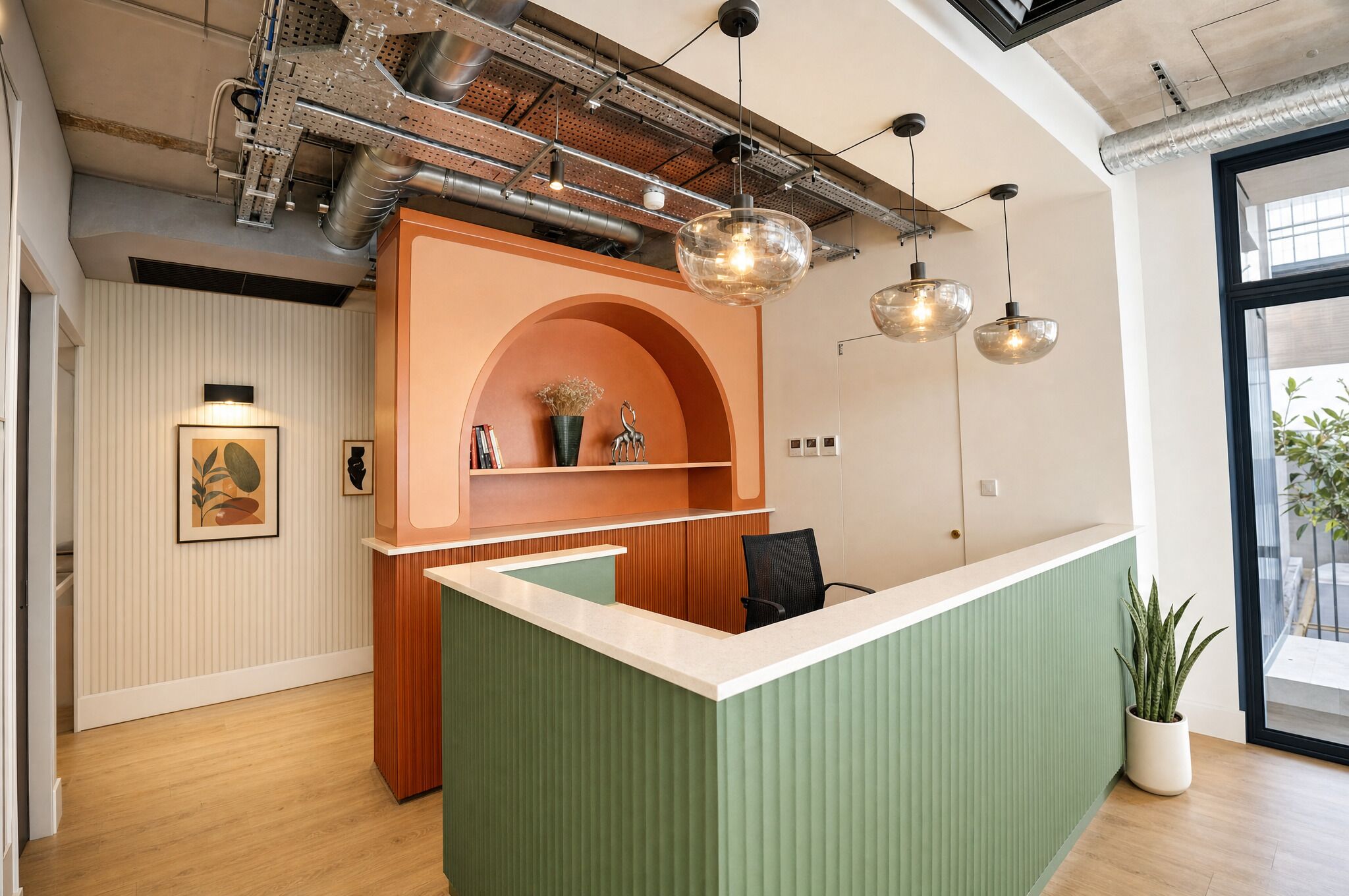 Una recepción con un mostrador verde, un arco de madera y una lámpara colgante.