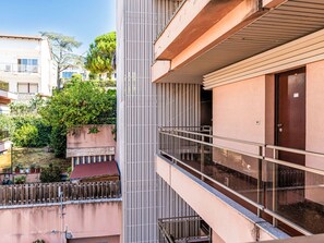 A modern building with a balcony, a wooden door, and a view of the surrounding area including trees and other buildings. - Il Nido by Interhome (Sanremo)